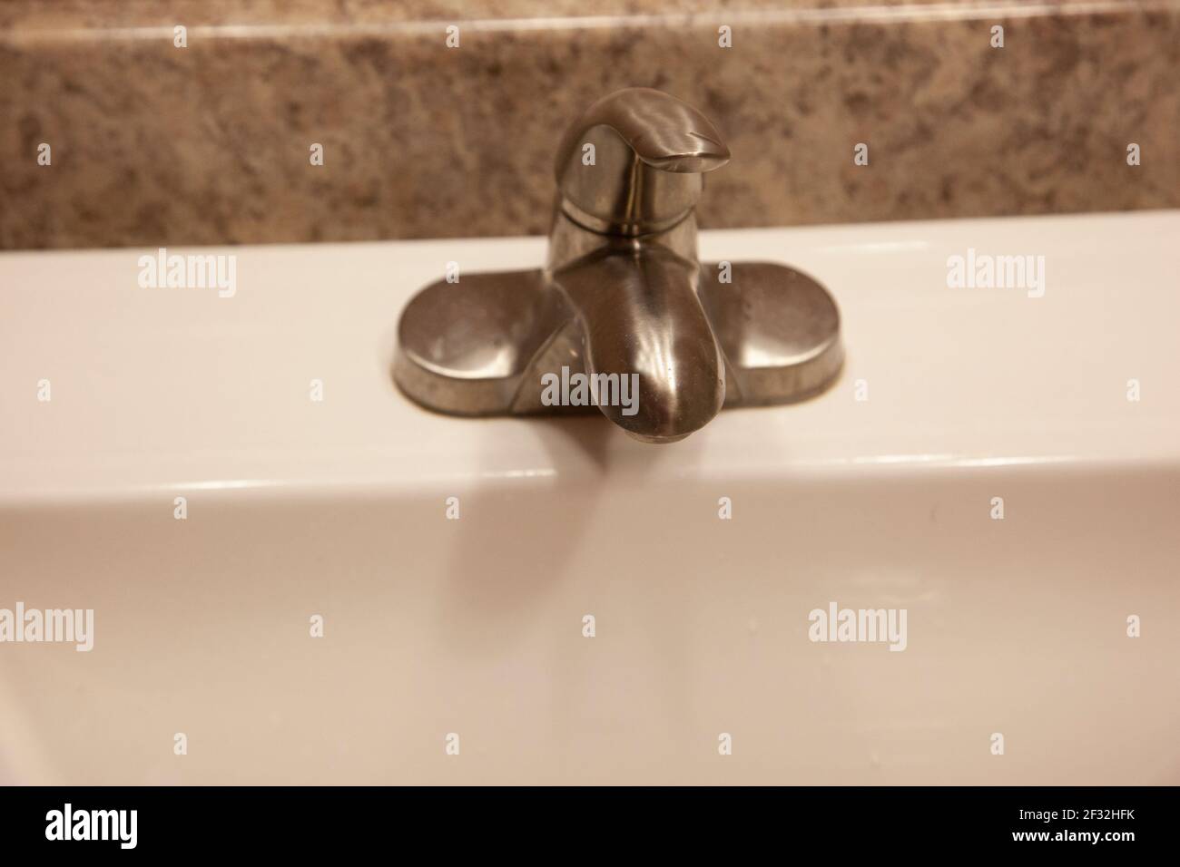 une poignée argentée pour allumer le robinet d'eau dans une maison avec comptoir en granit Banque D'Images