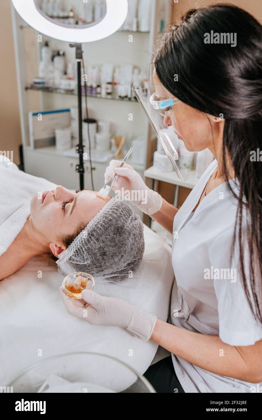 Esthéticienne ou facialiste faisant la procédure de nettoyage du visage à une femme dans un salon de beauté Banque D'Images