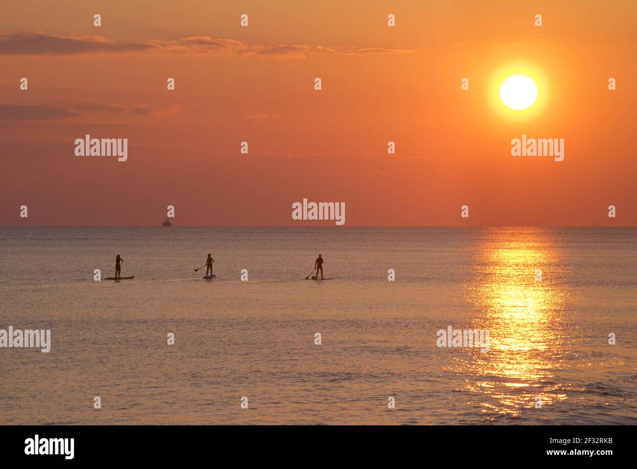 Brighton et Hove Beach au coucher du soleil. Silhouettes de paddleboard West Hove, East Sussex, Angleterre Banque D'Images