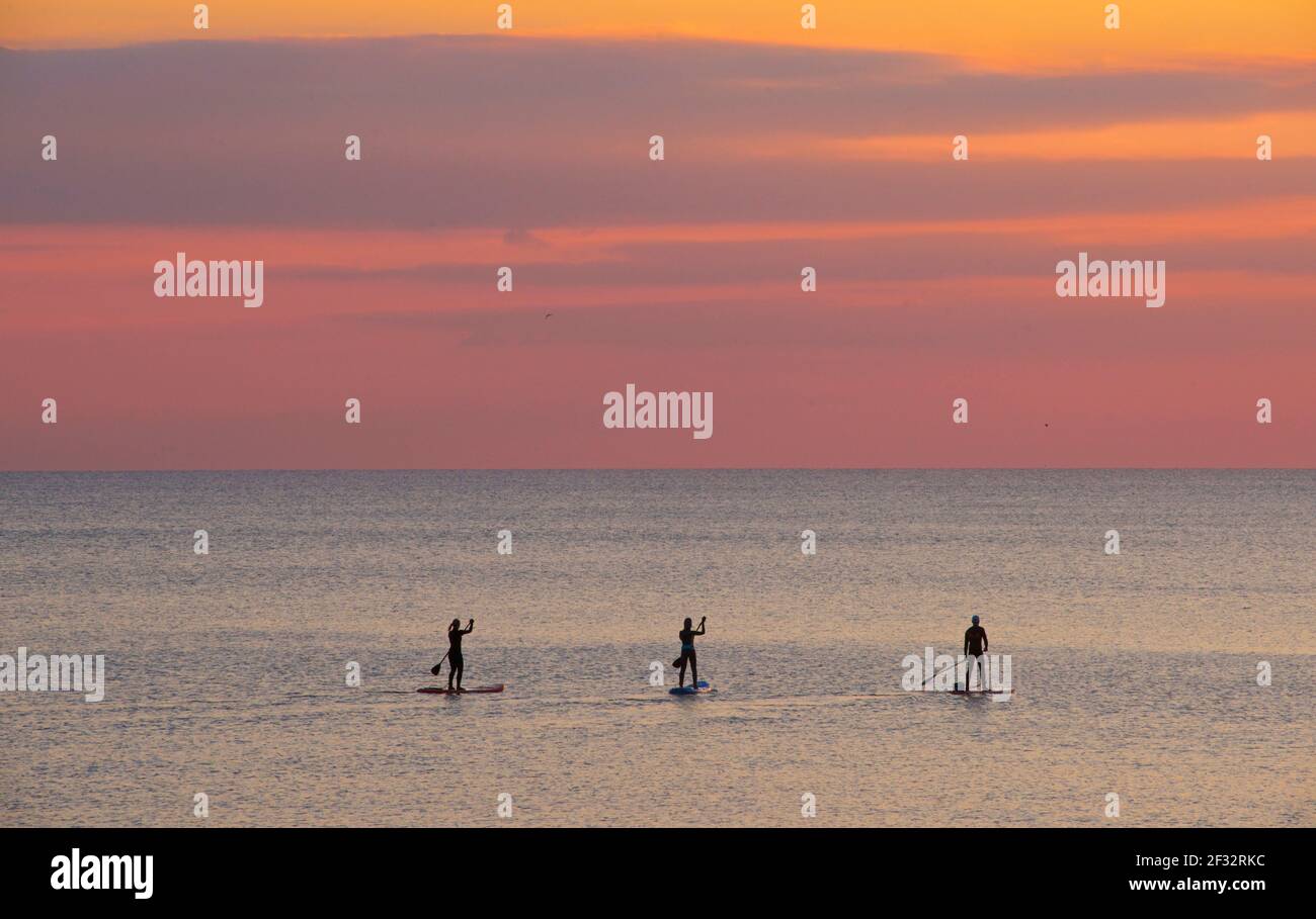 Brighton et Hove Beach au coucher du soleil. Silhouettes de paddleboard West Hove, East Sussex, Angleterre Banque D'Images