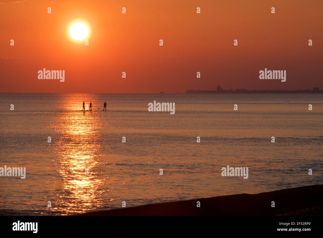 Brighton et Hove Beach au coucher du soleil. Silhouettes de paddleboard West Hove, East Sussex, Angleterre Banque D'Images