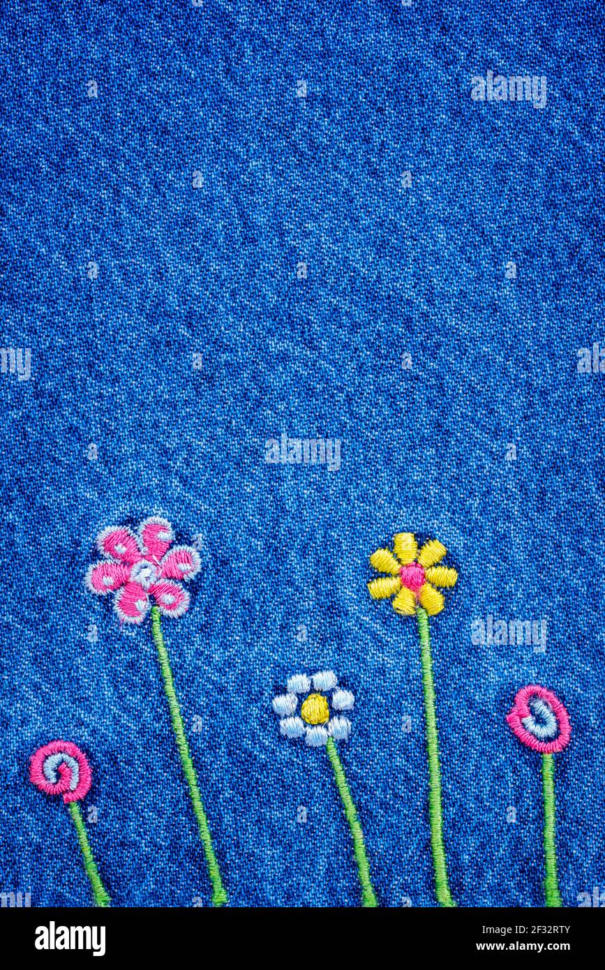 5 fleurs brodées sur un fragment de bleu denim Jean texture Banque D'Images