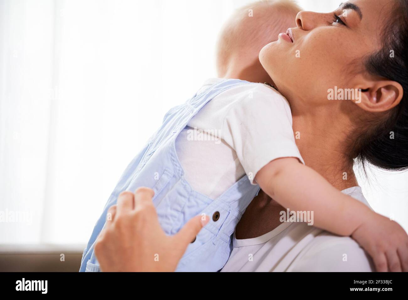 Image rognée d'une jeune femme de race mixte transportant son petit bébé à la maison Banque D'Images