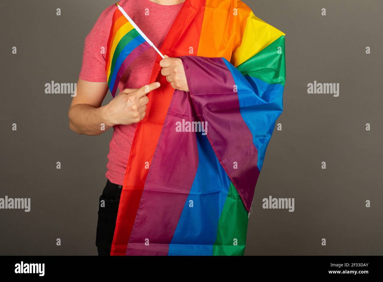 Homme gay portant un t-shirt rose et un drapeau arc-en-ciel Banque D'Images