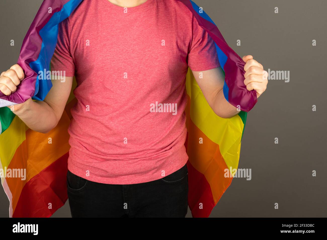 Homme gay portant un t-shirt rose et un drapeau arc-en-ciel Banque D'Images
