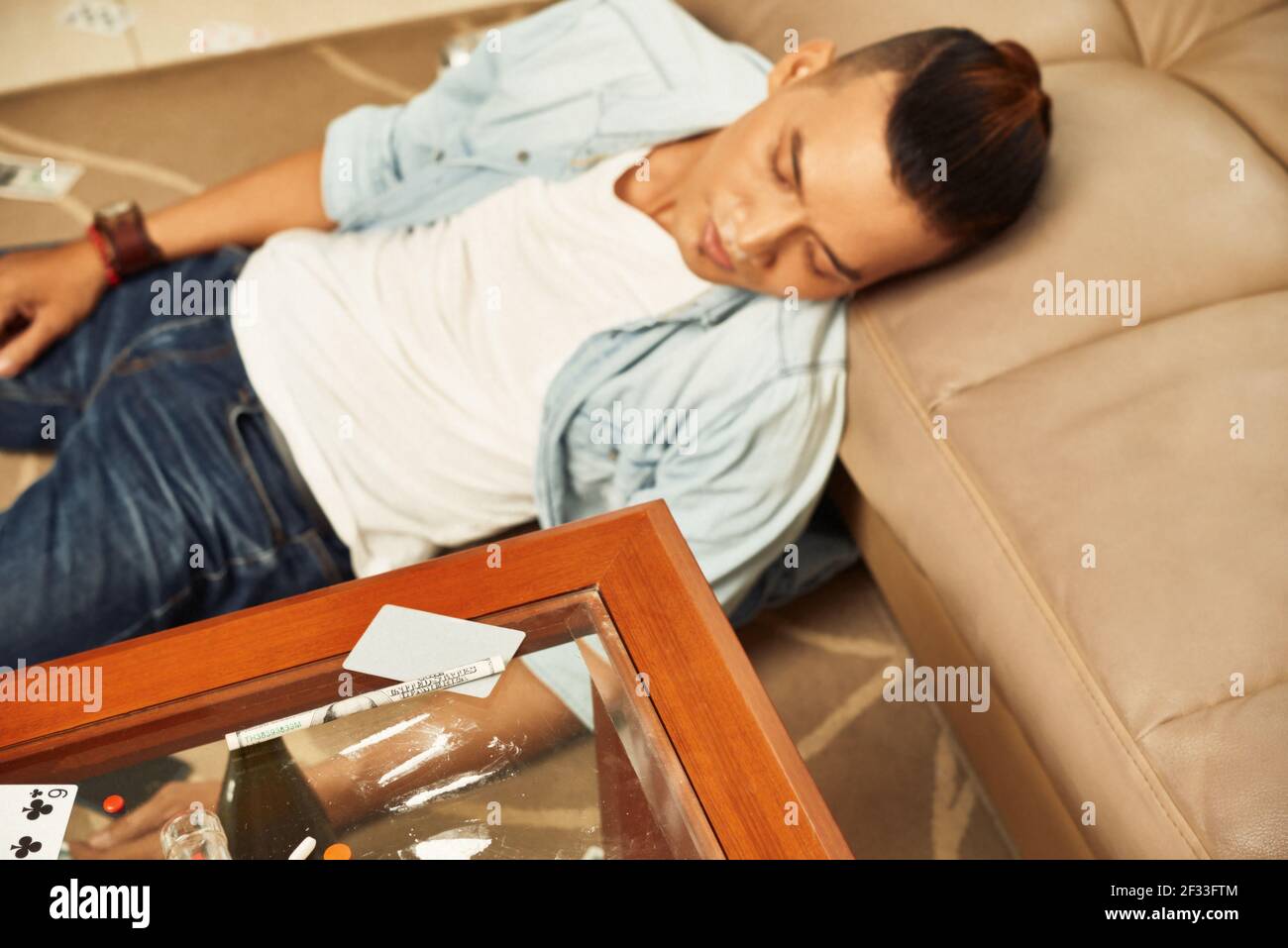 Le drogué s'est endormi sur le sol après avoir consommé de la cocaïne à la maison Banque D'Images