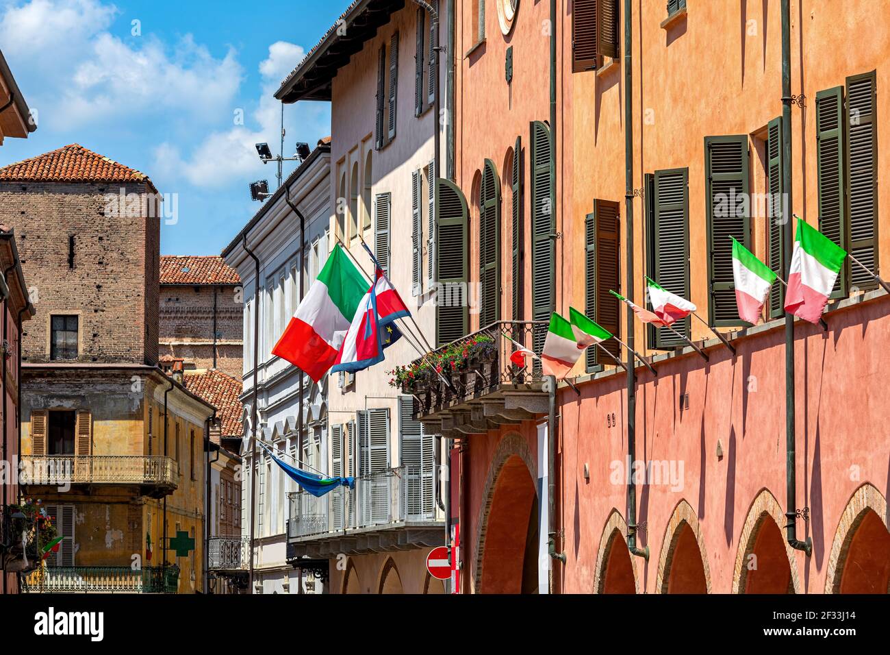 Drapeaux italiens ordonnant sur la façade et le balcon de l'hôtel de ville à Alba, Piémont, Italie du Nord. Banque D'Images