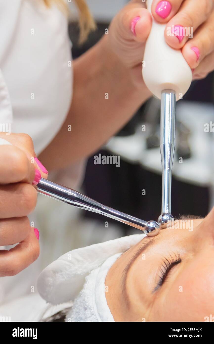 La fille est en train de subir une procédure dans un salon de beauté. Traitement anti-âge avec des médicaments à microcourants Banque D'Images La fille est en train de subir une procédure dans un salon de beauté. Traitement anti-âge avec des médicaments à microcourants Banque D'Images
