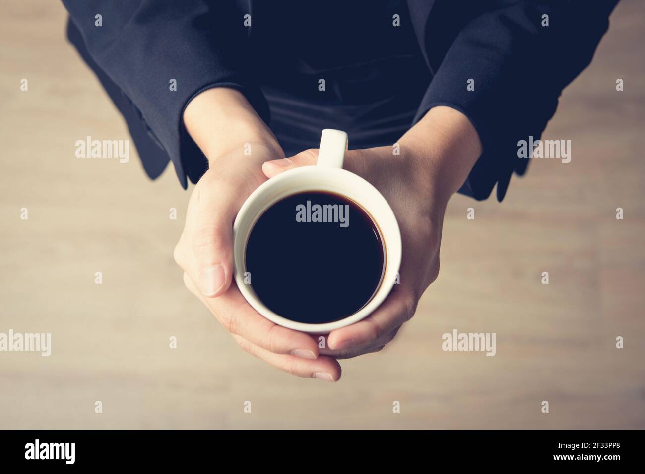 Femme mains tenant une tasse de café avec café noir - vue du dessus, effet de ton vintage Banque D'Images