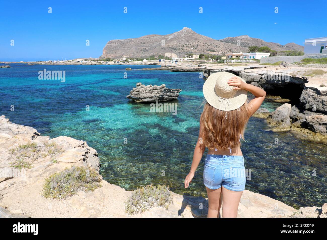 Voyageur fille avec de longs cheveux et chapeau avec la côte de mer cristalline sur Favignana, Sicile, Italie Banque D'Images