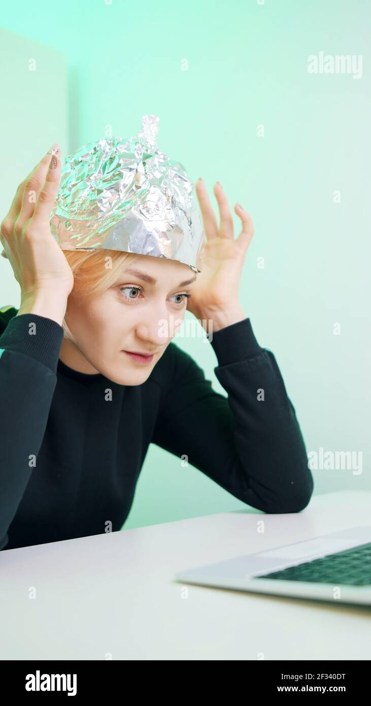 Verticale. Une jeune femme craintive avec un chapeau en aluminium  parcourant les médias sociaux. Théorie du complot sur les micro-ondes de 5g  . Photo de haute qualité Photo Stock - Alamy