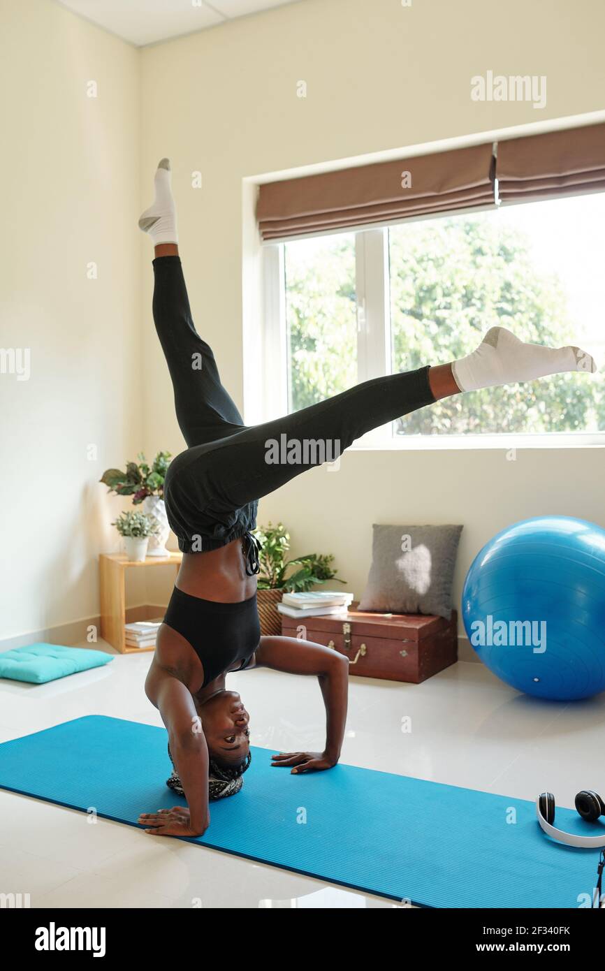 Posez la jeune femme noire faisant une tête soutenue sur le tapis de yoga lors de l'activité à la maison Banque D'Images