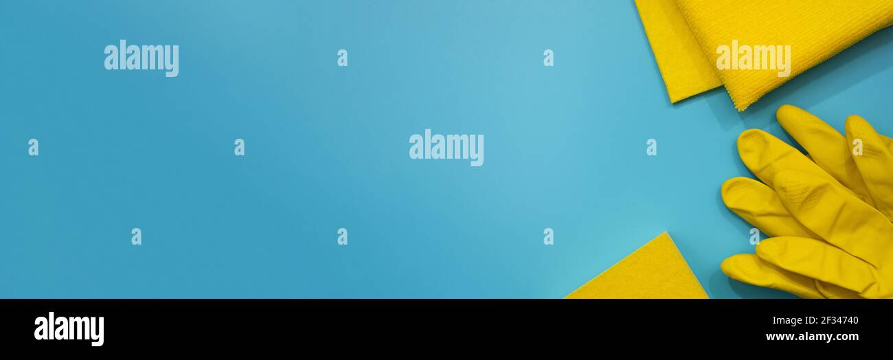 Gants de protection jaunes, éponge et chiffons sur fond bleu. Vue de dessus des fournitures de nettoyage. Bannière. Copier l'espace. Concept de nettoyage de la chambre de printemps Banque D'Images