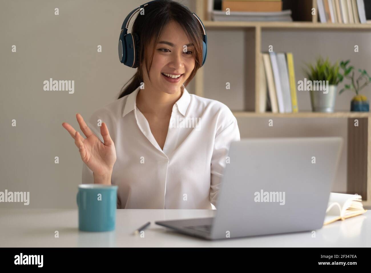 Belle femme asiatique dans les écouteurs ont vidéo appel classe à distance avec l'enseignant utilisant l'ordinateur portable - apprentissage en ligne concept. Banque D'Images