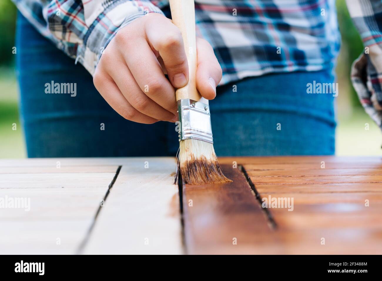 rénovation d'une table de jardin avec un pinceau et de l'huile par une jeune fille sur la terrasse Banque D'Images