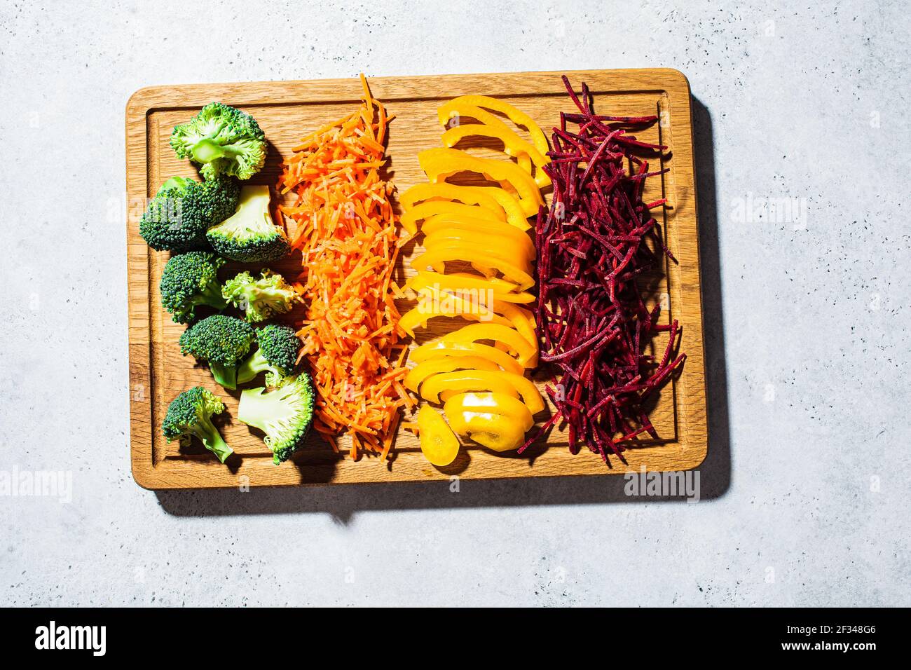 Tranches de légumes crus sur une planche de bois. Brocoli brut, poivrons, carottes et betteraves, vue du dessus. Cuisine saine concept. Banque D'Images