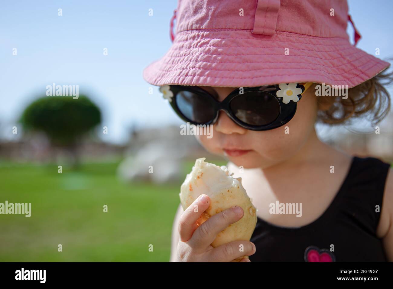 Petite fille drôle de manger des fruits exotiques en été dans le jardin sur un fond flou. Banque D'Images