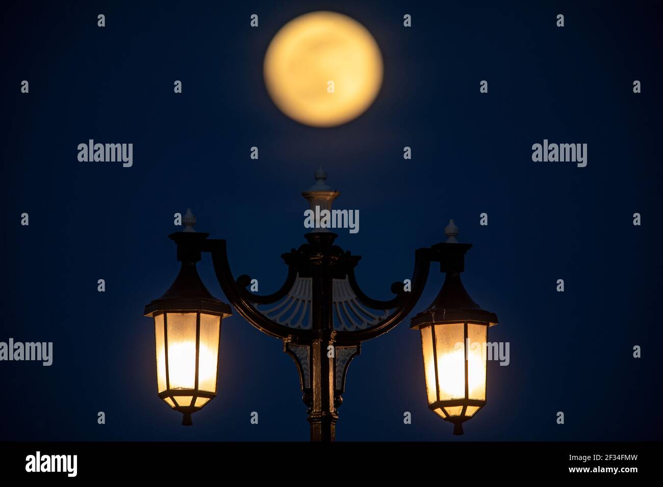 « Super Pink Moon » s'élève ce soir au-dessus des lumières de rue de la promenade Worthing, la plus grande pleine lune de 2020 Banque D'Images