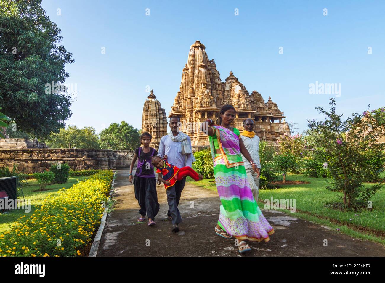 Khajuraho, Madhya Pradesh, Inde : une famille indienne passe devant le temple Lakshmana du Xe siècle, partie du groupe occidental de l'UNESCO World Heritag Banque D'Images