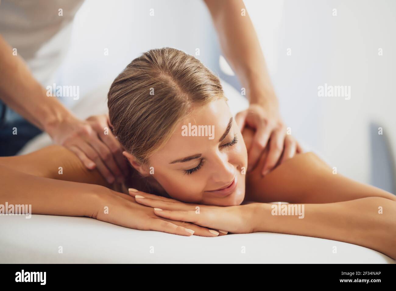 Masseur professionnel faisant un massage thérapeutique. Femme profitant d'un massage dans sa maison. Jeune femme se relaxant massage corporel. Banque D'Images
