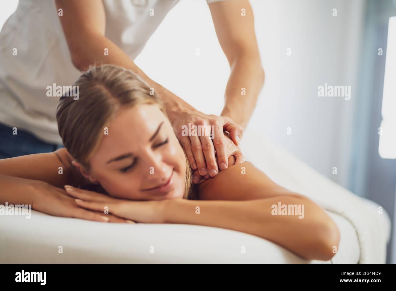 Masseur professionnel faisant un massage thérapeutique. Femme profitant d'un massage dans sa maison. Jeune femme se relaxant massage corporel. Banque D'Images
