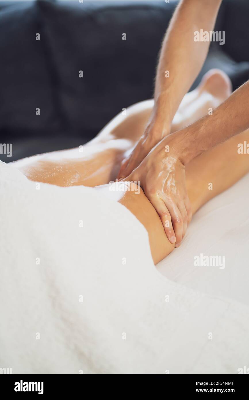 Masseur professionnel faisant un massage thérapeutique. Femme profitant d'un massage dans sa maison. Jeune femme se relaxant massage corporel. Banque D'Images