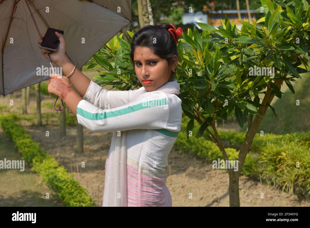 Indien Bengali adolescente fille coton blanc portant salwar kameez et dhupatta ouvrant un parapluie, focalisation sélective Banque D'Images