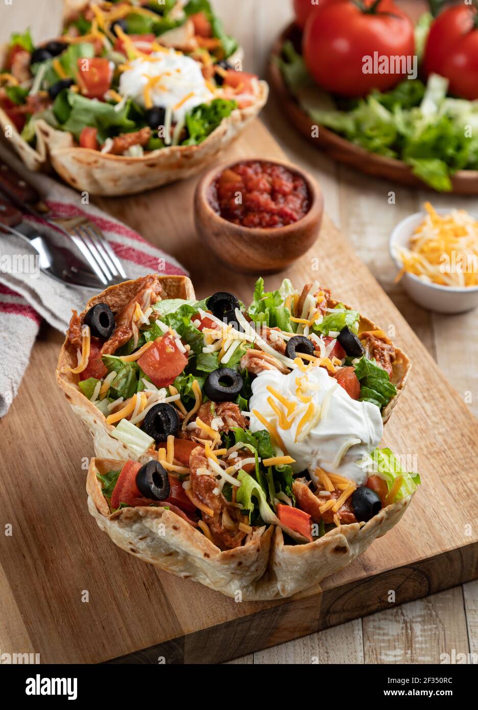 Salade de tacos faite avec du poulet, de la laitue, de la tomate, des olives noires, du fromage et de la crème sure dans une coquille de tortilla Banque D'Images