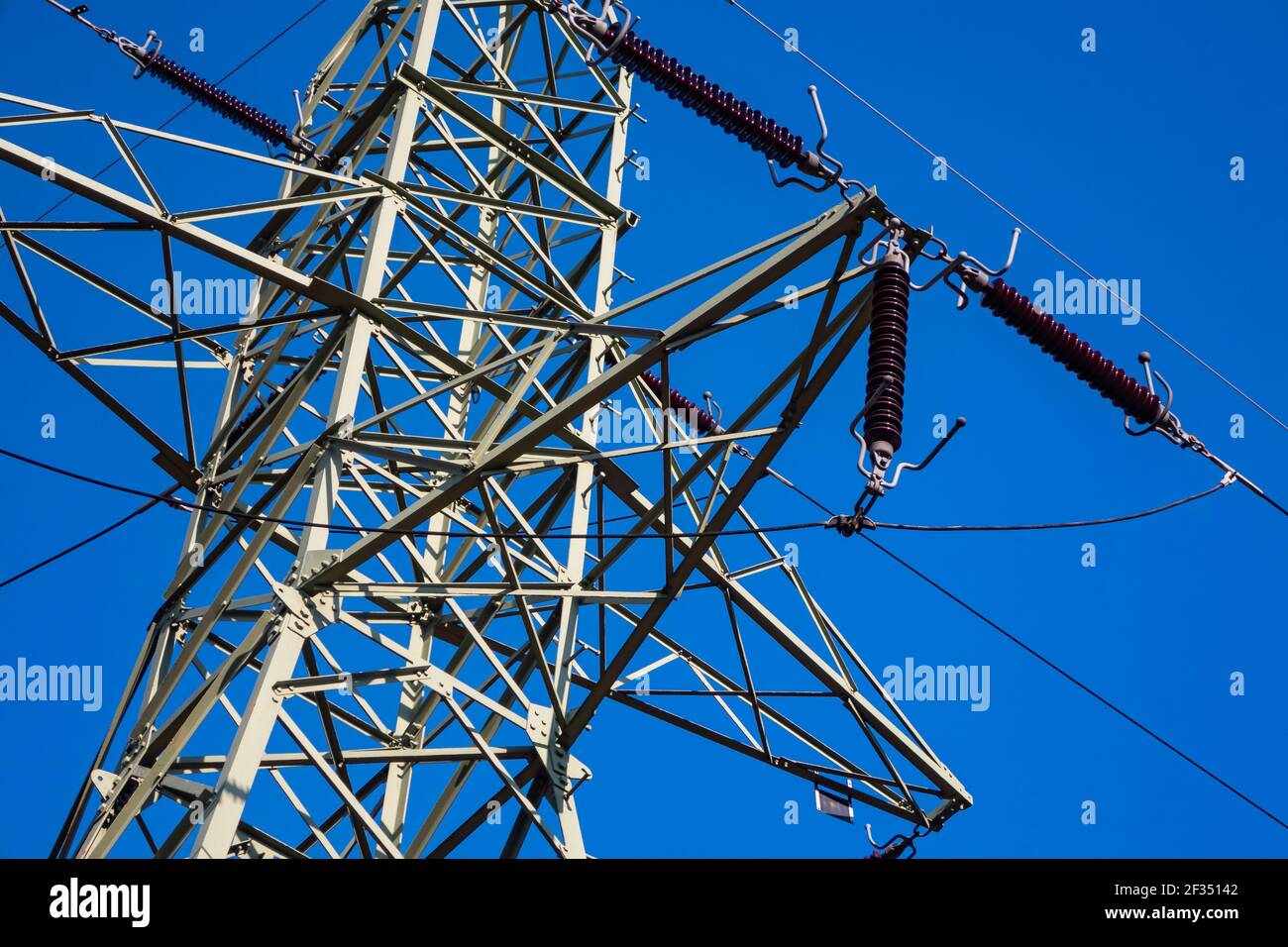 Gros plan des isolateurs sur les pylônes haute tension sur fond de ciel bleu. Fabriqué dans un ciel bleu profond et ensoleillé Banque D'Images