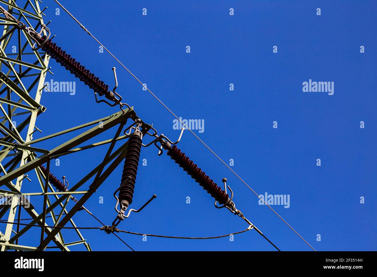 Gros plan des isolateurs sur les pylônes haute tension sur fond de ciel bleu. Fabriqué dans un ciel bleu profond et ensoleillé Banque D'Images