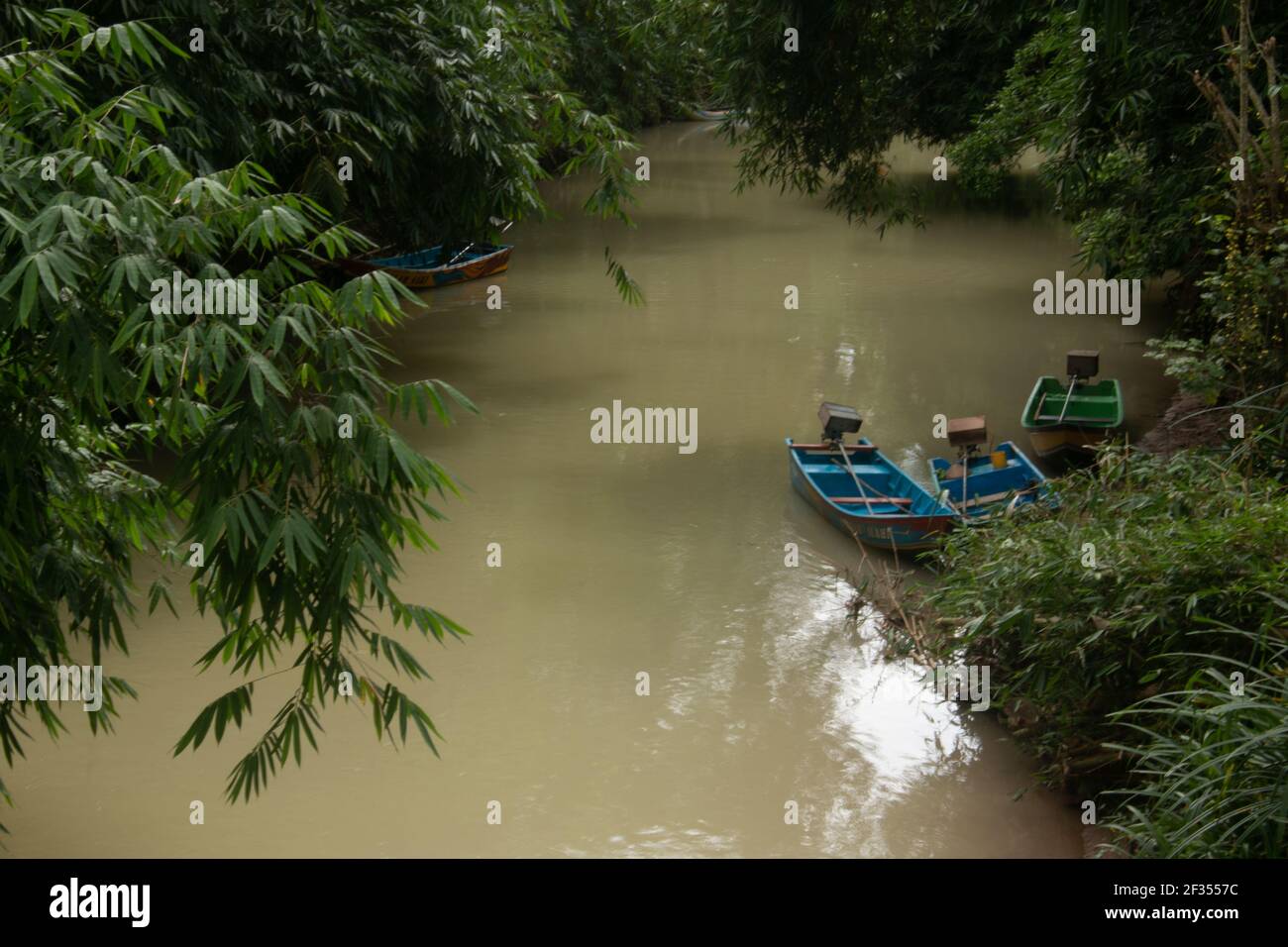 Une rivière marron vert flanquée d'arbres de forêt tropicale à Gunung Kidul sur Java, Indonésie avec de petits bateaux à moteur de pêcheur, Banque D'Images