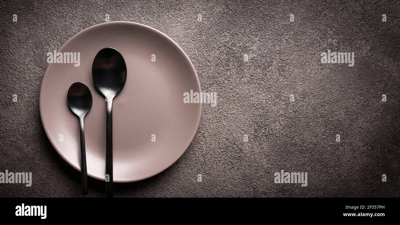 une assiette grise et des cuillères sur une table noire. copyspace concept pour la publicité des plats ou des menus de restaurant, une invitation à un dîner ou une célébration Banque D'Images