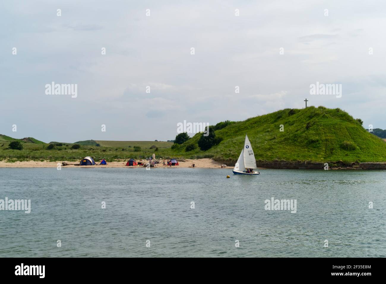 Un canot pneumatique Wayfarer navigue au-delà de St Cuthberts Cross sur Church Hill tandis que les gens campent sur la plage, Alnmouth, village côtier, Northumberland, Angleterre, Banque D'Images