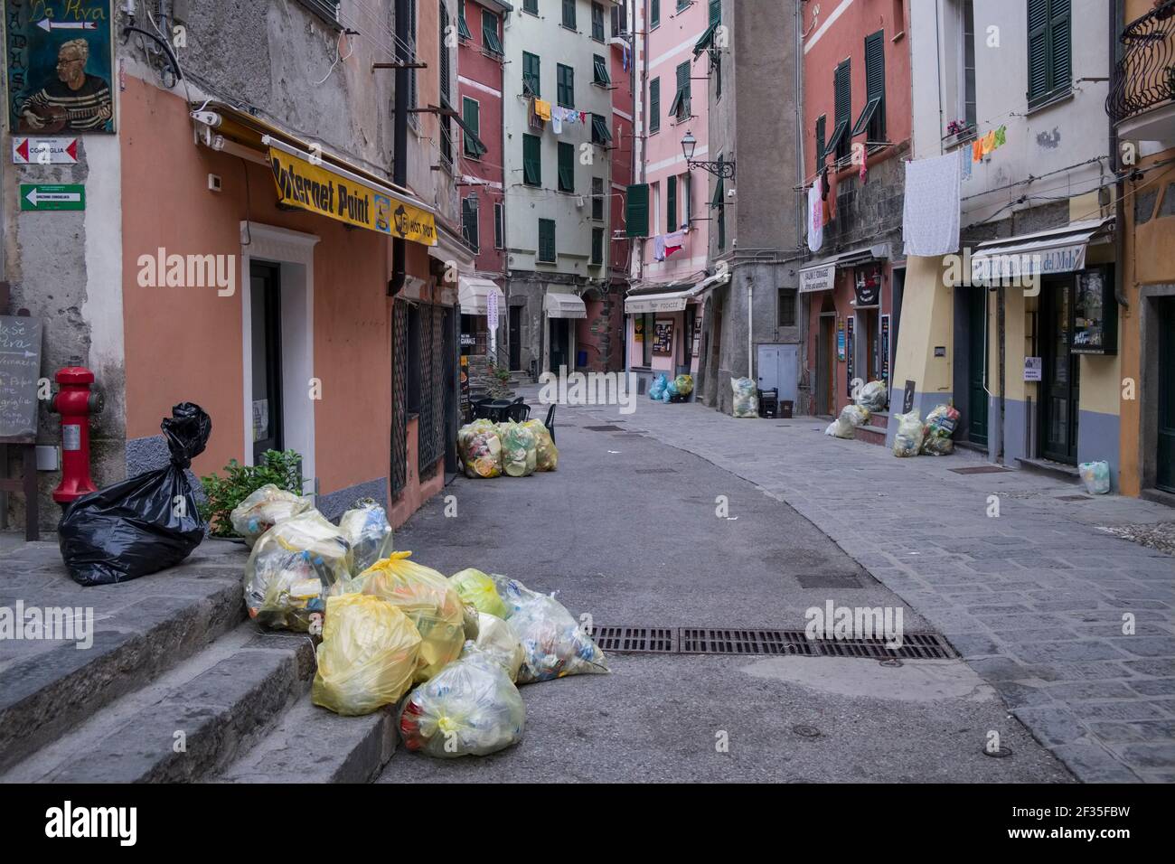 Italie, Ligurie : le village de Vernazza dans le parc national des Cinque Terre, site classé au patrimoine mondial de l'UNESCO. Sacs de recyclage de déchets ménagers dans une rue Banque D'Images