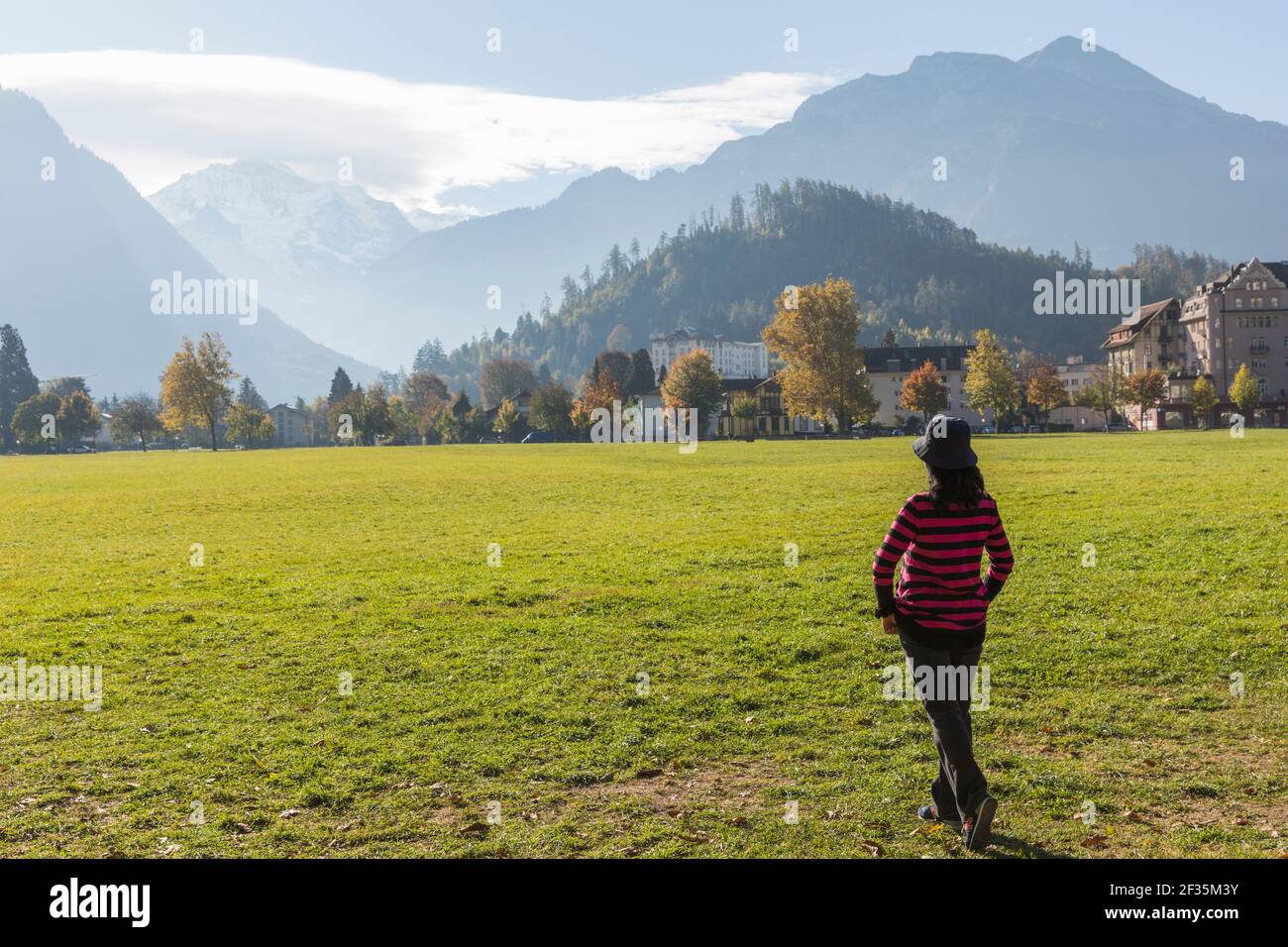 Suisse, Interlaken, femme regardant vers les Alpes suisses à travers un pré vert. Banque D'Images