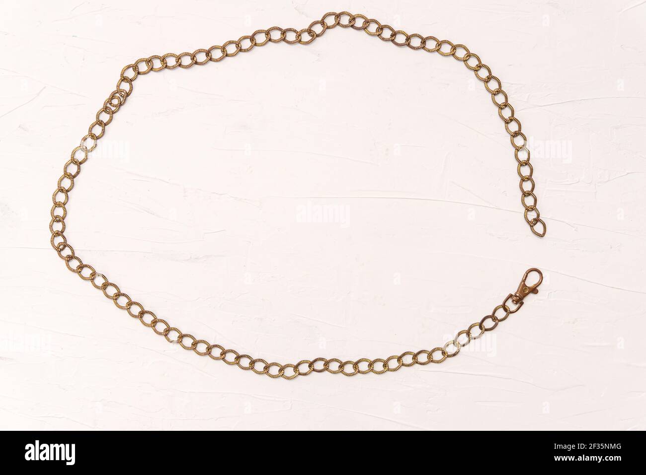 Cadre ovale rétro de l'accessoire de mode ancienne ceinture en métal doré chaîne avec fermoir ouvert dans un cadre arrondi sur fond blanc Banque D'Images