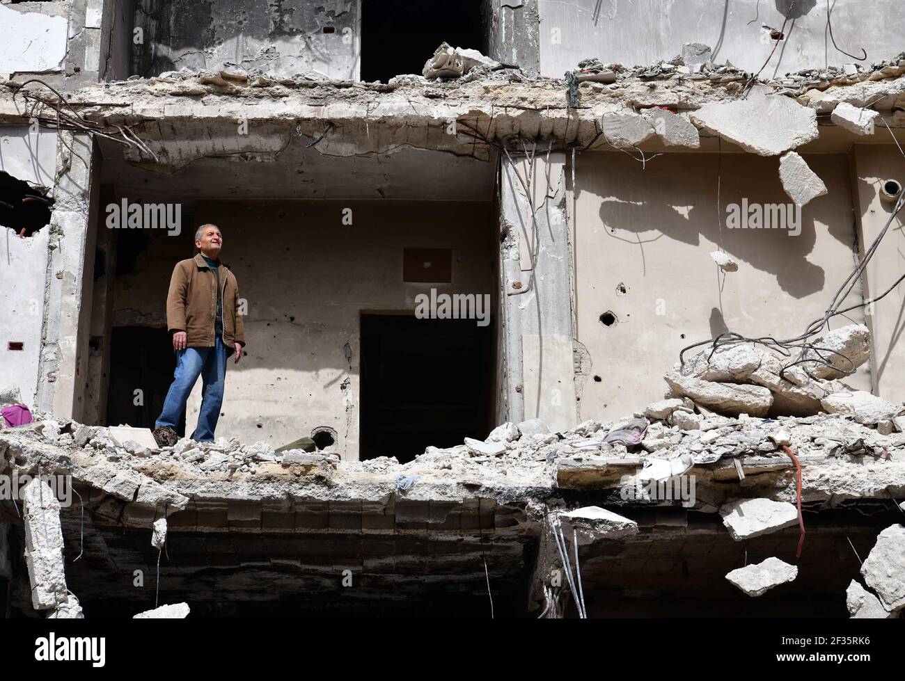 Homs, ville de Homs dans le centre de la Syrie. 11 mars 2021. Hadi Ghusoun, professeur d'anglais à la retraite à la fin des années 60, se trouve sur le porche de sa maison brisée dans la ville de Homs, dans le centre de la Syrie, le 11 mars 2021. POUR ALLER AVEC: 'Feature: Après 10 ans de guerre syrienne, les personnes âgées abandonnent l'espoir de retourner à la maison' crédit: Ammar Safarjalani/Xinhua/Alay Live News Banque D'Images