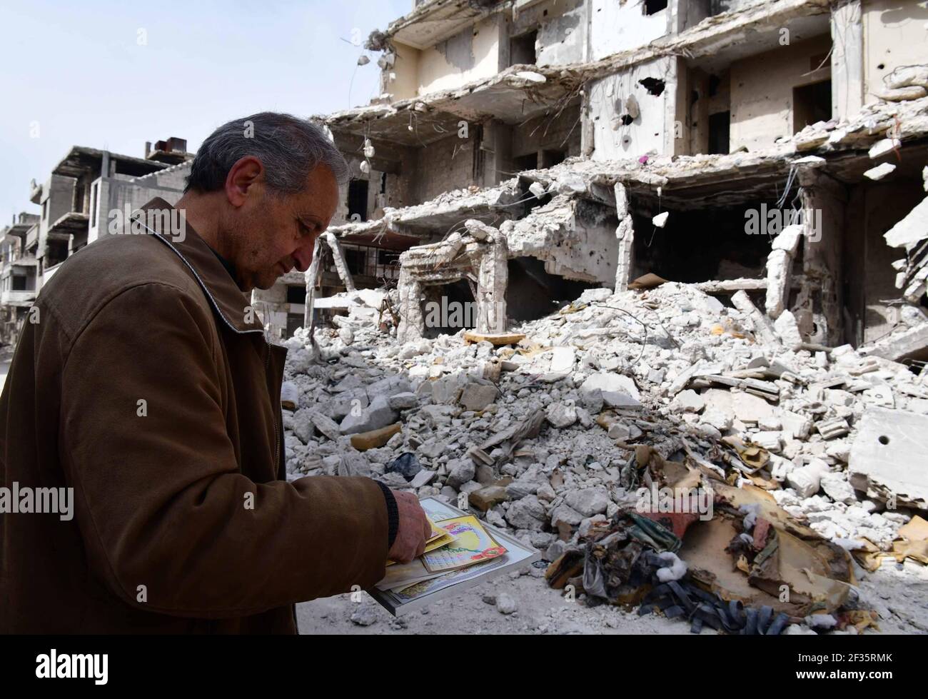 Homs, ville de Homs dans le centre de la Syrie. 11 mars 2021. Hadi Ghusoun, professeur d'anglais à la retraite à la fin des années 60, regarde d'anciens certificats qu'il avait trouvés sous les décombres de sa maison brisée dans la ville de Homs, dans le centre de la Syrie, le 11 mars 2021. POUR ALLER AVEC: 'Feature: Après 10 ans de guerre syrienne, les personnes âgées abandonnent l'espoir de retourner à la maison' crédit: Ammar Safarjalani/Xinhua/Alay Live News Banque D'Images