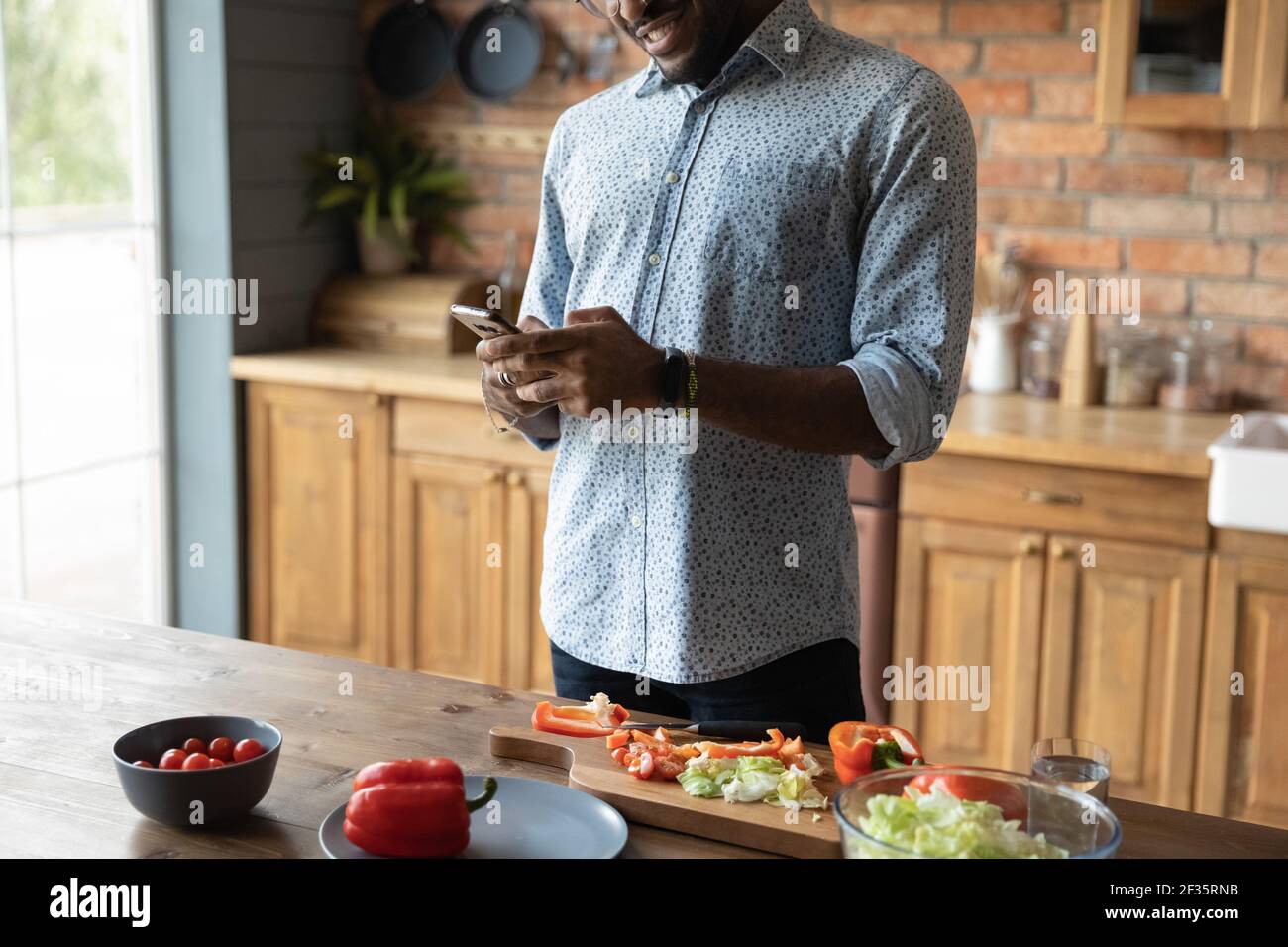 Un homme africain utilise une cellule pour rechercher une recette de cuisine en ligne Banque D'Images