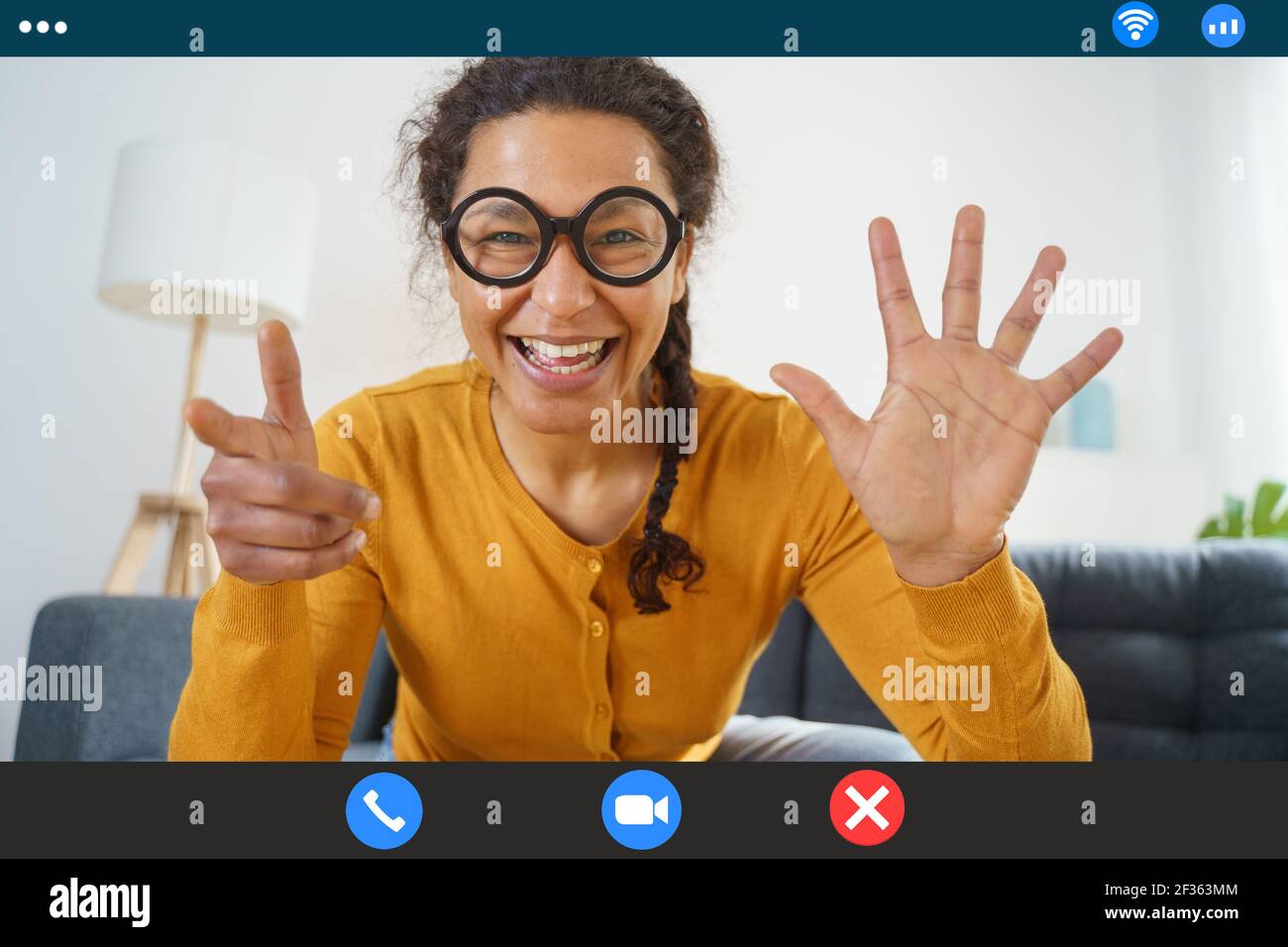Bonne femme noire qui passe un appel vidéo depuis sa maison Banque D'Images