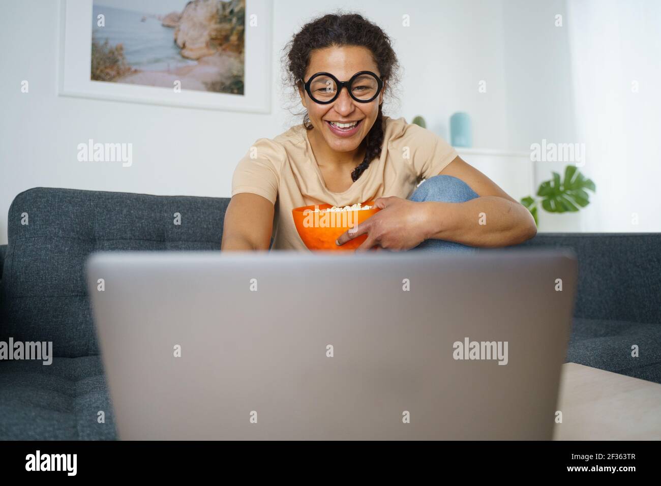 Une femme afro-américaine joyeuse regardant en streaming youtube Banque D'Images