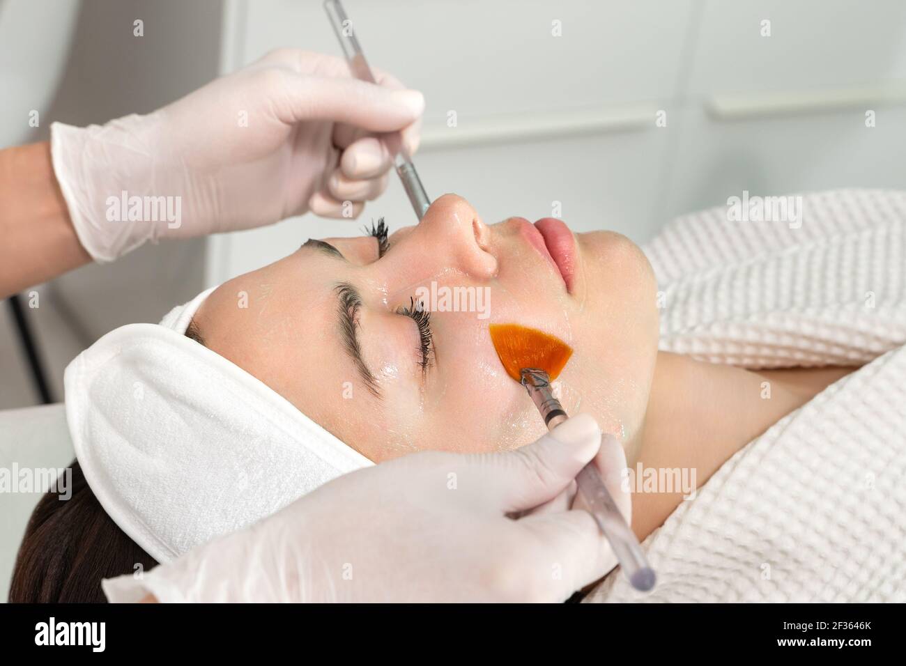 Soin du visage. Un masque est appliqué à un visage de femme dans une clinique de cosmétologie. Gros plan Banque D'Images