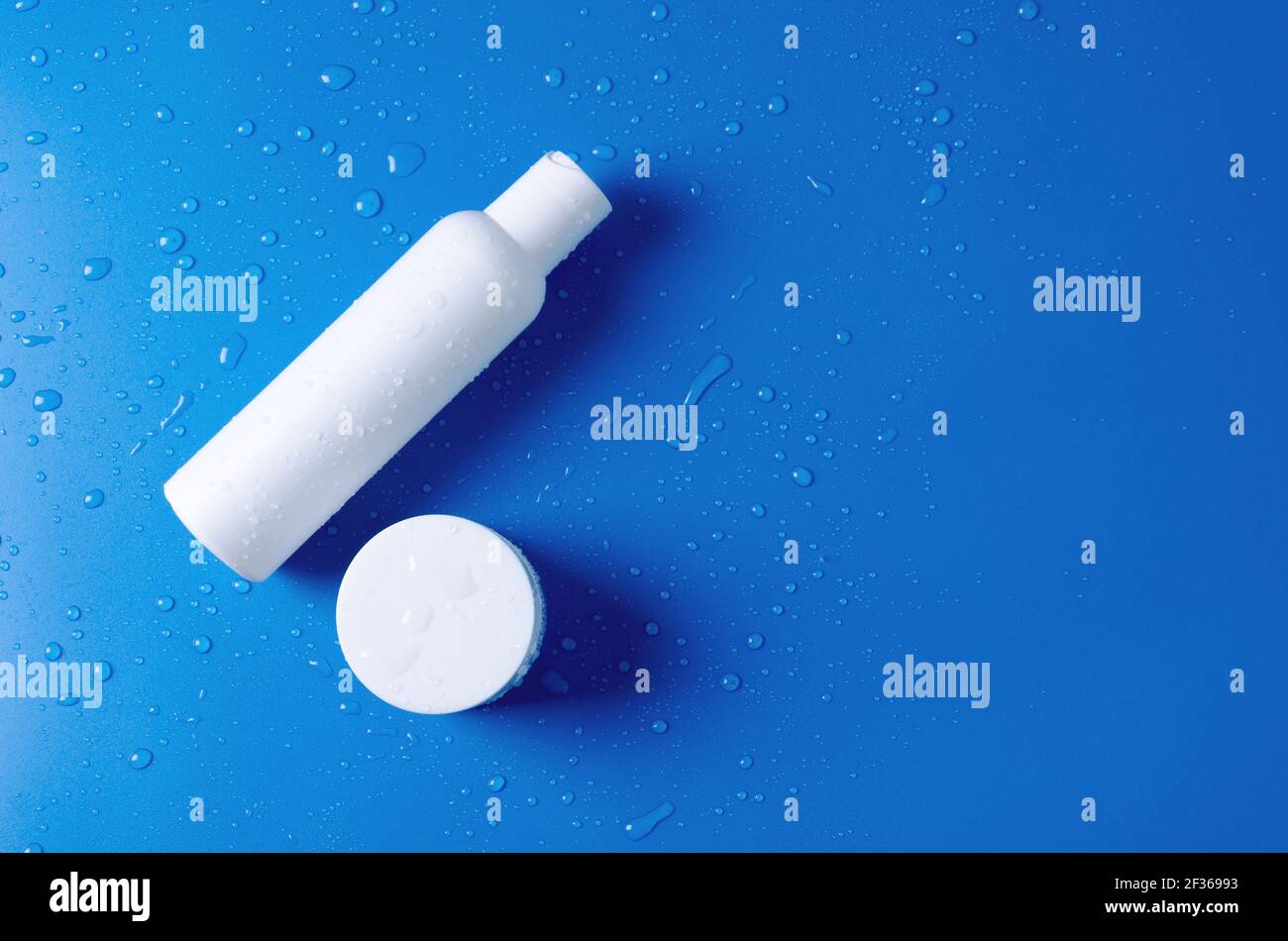 Concept de modèle pour la vente d'un produit cosmétique. Bouteille cosmétique blanche avec lotion, eau, crème et pot de crème pour le soin du visage sur fond bleu Banque D'Images