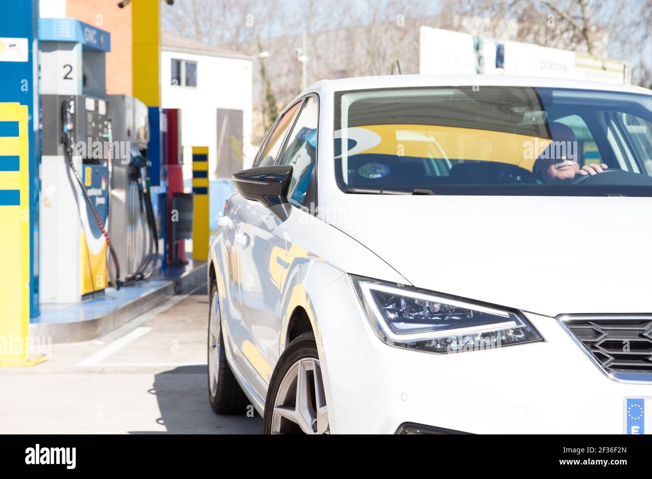 Un homme plus âgé qui sort avec sa voiture verte de la station-service. Avec la pompe à gaz naturel comprimé (GNC) derrière le véhicule. Énergie durable conce Banque D'Images