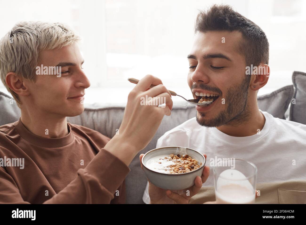 Portrait d'un couple gai amusant prenant le petit déjeuner ensemble, concentrez-vous sur le sourire jeune homme nourrissant un petit ami Banque D'Images