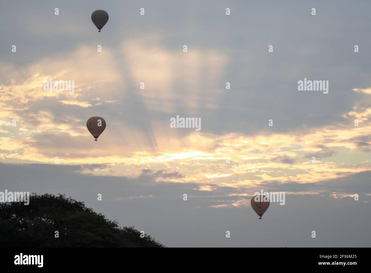 BAGAN, NYAUNG-U, MYANMAR - 2 JANVIER 2020 : trois ballons à air chaud dans le ciel au lever du soleil tôt le matin, par une journée nuageux Banque D'Images