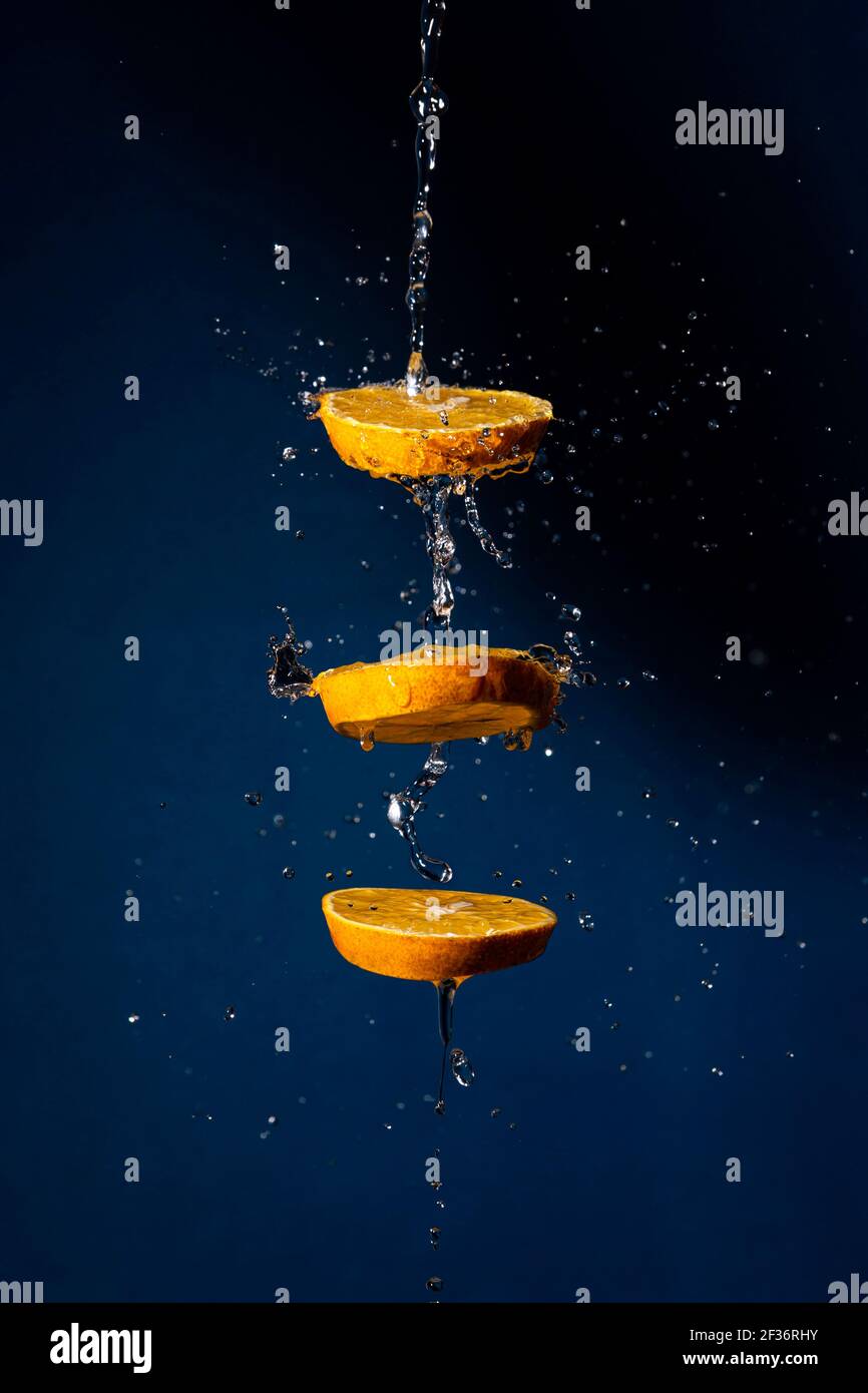 illustration de la quantité de tranches d'orange avec projection d'eau dans l'obscurité arrière-plan bleu Banque D'Images