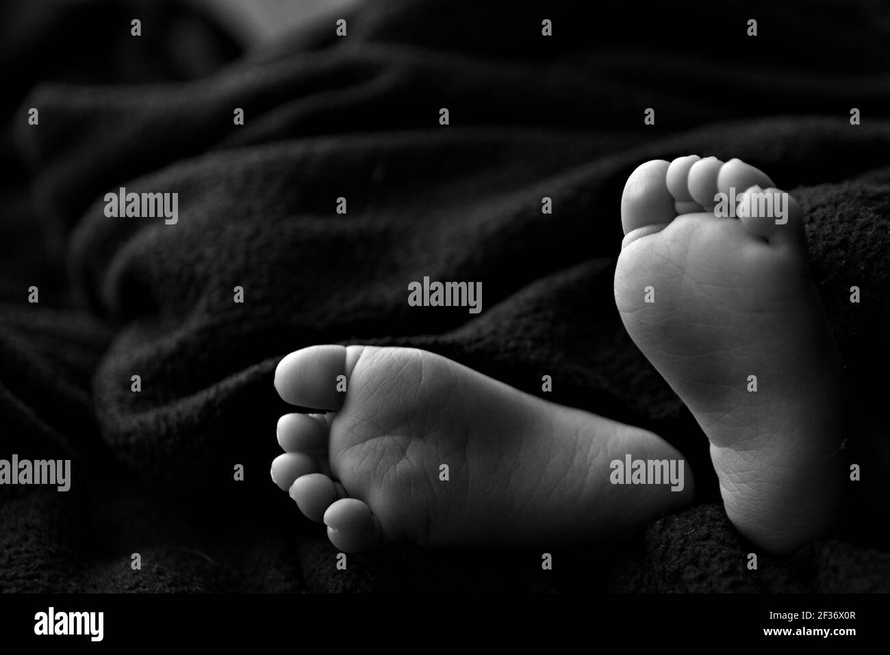 Les pieds de bébé sur fond noir en noir et blanc avec espace pour le titre ou le texte Banque D'Images