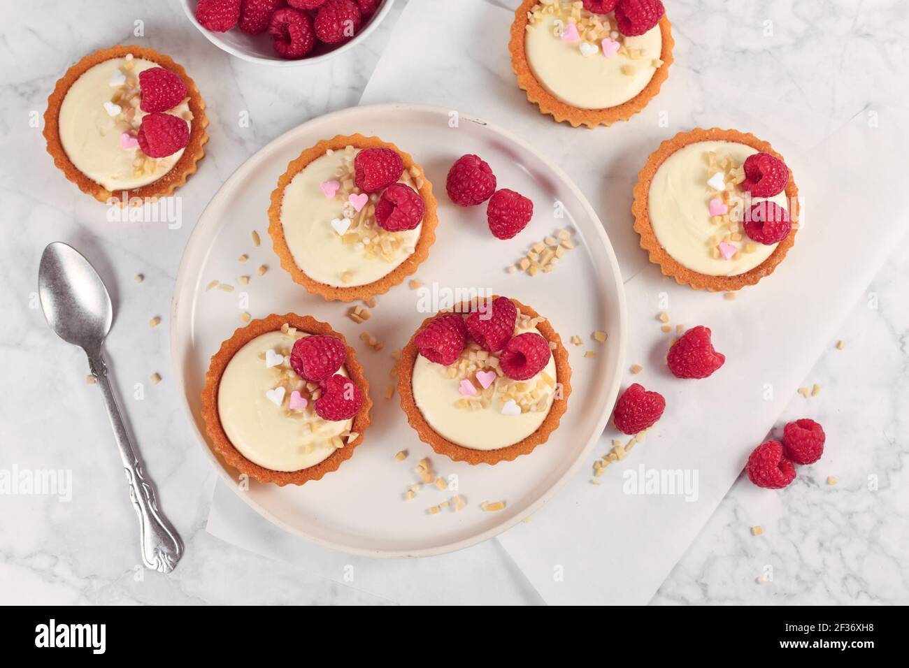 Petites pâtisseries tartelettes à la crème blanche, nappées de fruits à la framboise et de saupoudrés d'amandes Banque D'Images