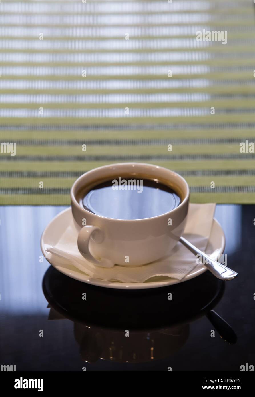 Tasse de café sur une soucoupe sur une table près d'un fenêtre avec fenêtre Banque D'Images